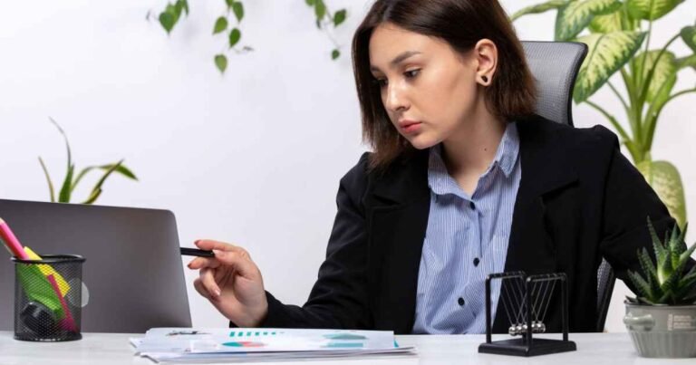 A beautiful young businesswoman working on a laptop at a desk in an office.